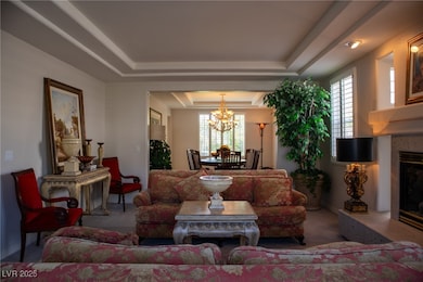 Living room with a tray ceiling, a chandelier, car