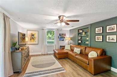 Living room with ceiling fan, light wood-style flo