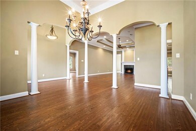 Unfurnished living room featuring ceiling fan, a premium fireplace, dark wood finished floors, crown molding, and plenty of natural light