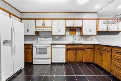 Kitchen with white cabinetry, dark tile patterned 