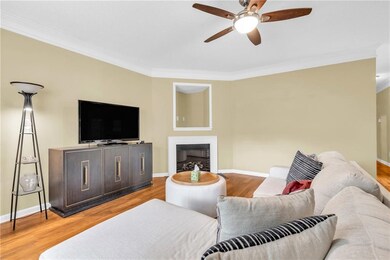 Living area featuring crown molding, ceiling fan, wood finished floors, and a fireplace