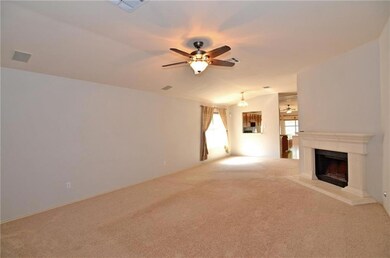 Unfurnished living room with ceiling fan, carpet, and a fireplace with raised hearth