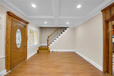 Foyer featuring ornamental molding, coffered ceiling, light hardwood / wood-style flooring, and beamed ceiling