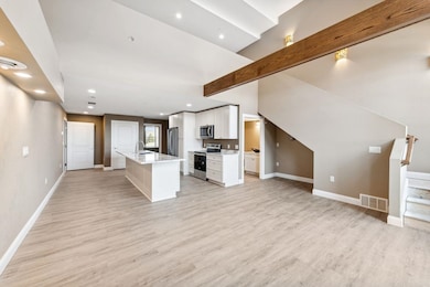 Unfurnished living room with sink, beam ceiling, and light wood-type flooring