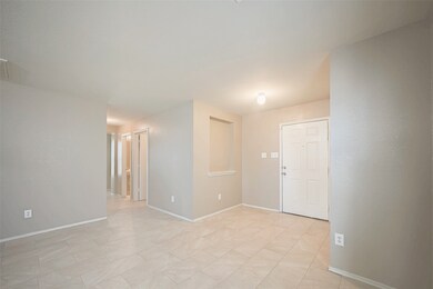 Bright, neutral-toned entryway with tiled flooring. The space is open, leading to a hallway with visible doors, offering a clean and welcoming atmosphere.