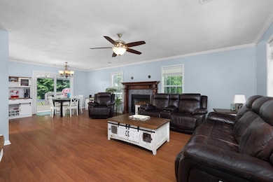 Living room with a ceiling fan, dark wood-type flooring, a chandelier, a tiled fireplace, and a textured ceiling