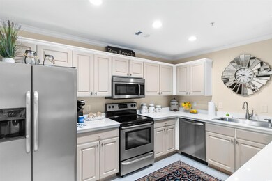 Kitchen with appliances with stainless steel finishes, crown molding, light countertops, white cabinetry, and recessed lighting