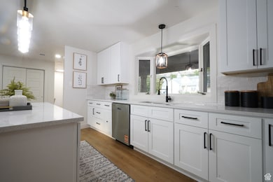Kitchen featuring decorative light fixtures, dark wood finished floors, white cabinets, and light stone counters