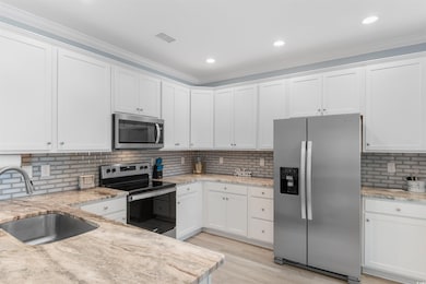 Kitchen with white cabinets, a sink, light stone c