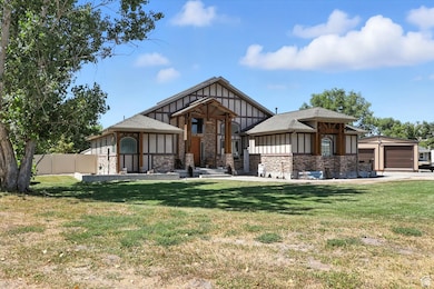 View of front of house featuring board and batten siding, stone siding, an outbuilding, and roof with shingles