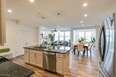 Kitchen with wide open view, appliances with stainless steel finishes, center island with sink, easy-flow floor plan, and plank wood-like flooring.