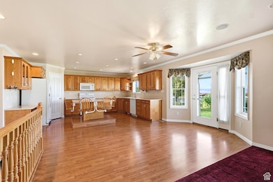 Kitchen with a kitchen breakfast bar, light countertops, crown molding, light wood-style floors, and brown cabinetry