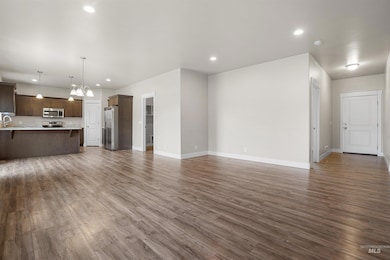 Unfurnished living room featuring dark wood-style flooring, recessed lighting, and a chandelier