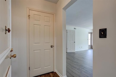 Hallway featuring dark wood-style flooring, baseboards, and ornamental molding