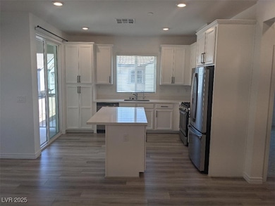 Kitchen featuring white cabinets, appliances with stainless steel finishes, a kitchen island, dark wood-style floors, and recessed lighting