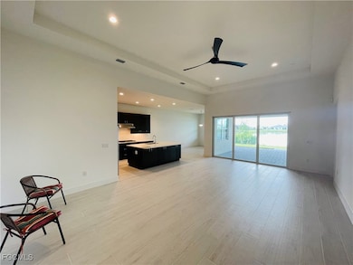 Unfurnished living room with a raised ceiling, recessed lighting, light wood-style floors, and ceiling fan