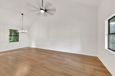 Formal living room with lofted ceiling, light wood-style floors, a chandelier, and baseboards