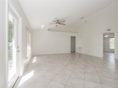 Unfurnished room with a ceiling fan, vaulted ceiling, and light tile patterned floors