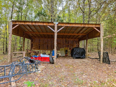 View of pole building with a detached carport and a view of trees