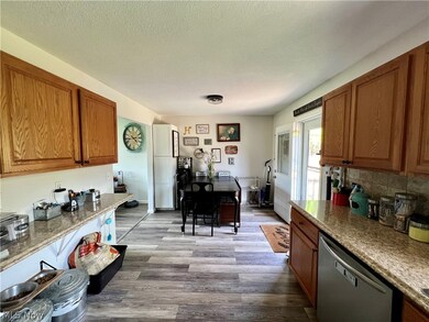 Kitchen with stone countertops, a textured ceiling, tasteful backsplash, stainless steel dishwasher, and hardwood / wood-style floors