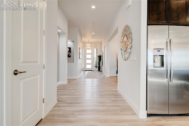 Hallway with recessed lighting, light wood-style flooring, and a chandelier