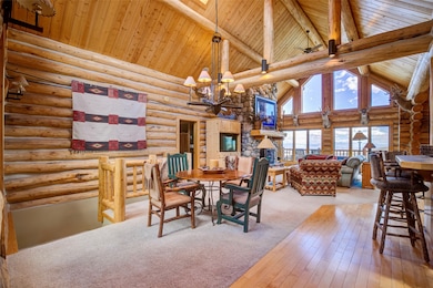Dining room featuring an inviting chandelier, log walls, high vaulted ceiling, wood ceiling, and beam ceiling