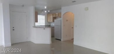 Kitchen with arched walkways, freestanding refrigerator, light tile patterned floors, a peninsula, and light countertops