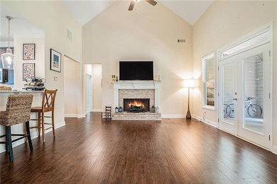 Living area with wood finished floors, high vaulted ceiling, ceiling fan, a fireplace, and baseboards