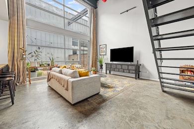 Living room featuring a towering ceiling, concrete floors, and stairs