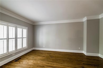 Spare room with ornamental molding, baseboards, and dark wood-style flooring