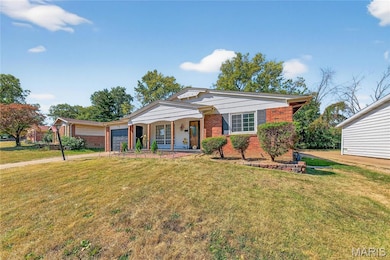 View of front of home with brick siding, a front lawn, a garage, and a porch