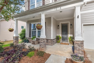 Stately columns and stone accents frame the charming front porch, where a beautiful glass storm door offers a welcoming entry and light into the home.