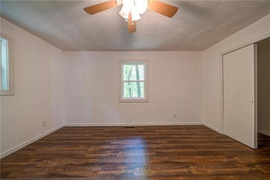 Unfurnished bedroom featuring dark wood-style flooring, a textured ceiling, ceiling fan, baseboards, and a closet