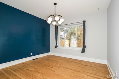 Spare room featuring hardwood / wood-style floors and a chandelier