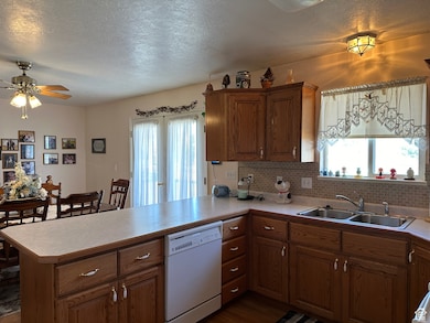 Kitchen with a textured ceiling, dishwasher, brown cabinets, decorative backsplash, and light countertops