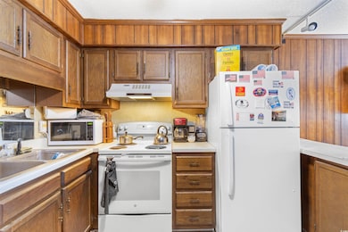 Kitchen with brown cabinetry, under cabinet range 