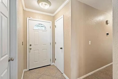 Entryway featuring ornamental molding and light tile patterned floors