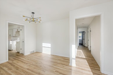 Unfurnished dining area featuring light wood-style flooring, attic access, and a chandelier