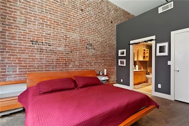 Bedroom featuring connected bathroom, brick wall, 