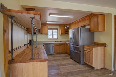 Kitchen featuring butcher block counters, appliances with stainless steel finishes, dark wood finished floors, and glass insert cabinets