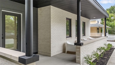 View of side of home featuring a porch and brick siding