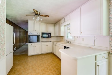Kitchen featuring black appliances, ceiling fan, a peninsula, and light countertops