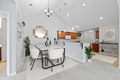 Dining area featuring high vaulted ceiling, a chandelier, light carpet, and recessed lighting- photo has been digitally staged.