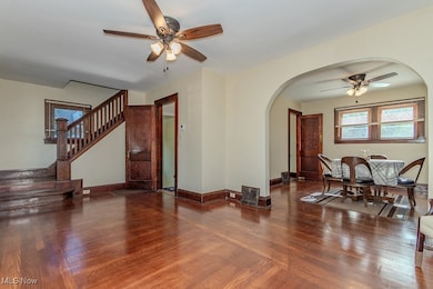 Living area featuring a ceiling fan, wood finished floors, stairway, and arched walkways
