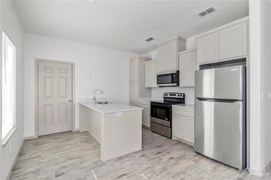 Kitchen featuring appliances with stainless steel finishes, a peninsula, white cabinets, light wood-style flooring, and recessed lighting