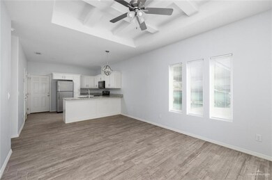 Kitchen with a peninsula, light wood finished floors, baseboards, stainless steel appliances, and white cabinetry