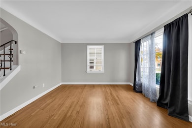 Spare room with stairs, arched walkways, wood finished floors, and healthy amount of natural light