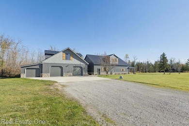 View of front of property with driveway, a front lawn, stone siding, and an attached garage