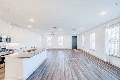 Kitchen with appliances with stainless steel finishes, white cabinetry, a kitchen island with sink, recessed lighting, and open floor plan