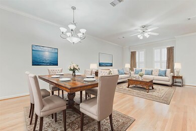 The formal dining area sits just off the living room, defined by a beautiful chandelier and framed by crisp white trim and wide-open wall space—perfect for showcasing art or mirrors. Rich wood floors flow throughout, creating continuity and elegance ideal for dinner parties or casual meals alike. Thoughtful proportions make entertaining effortless.